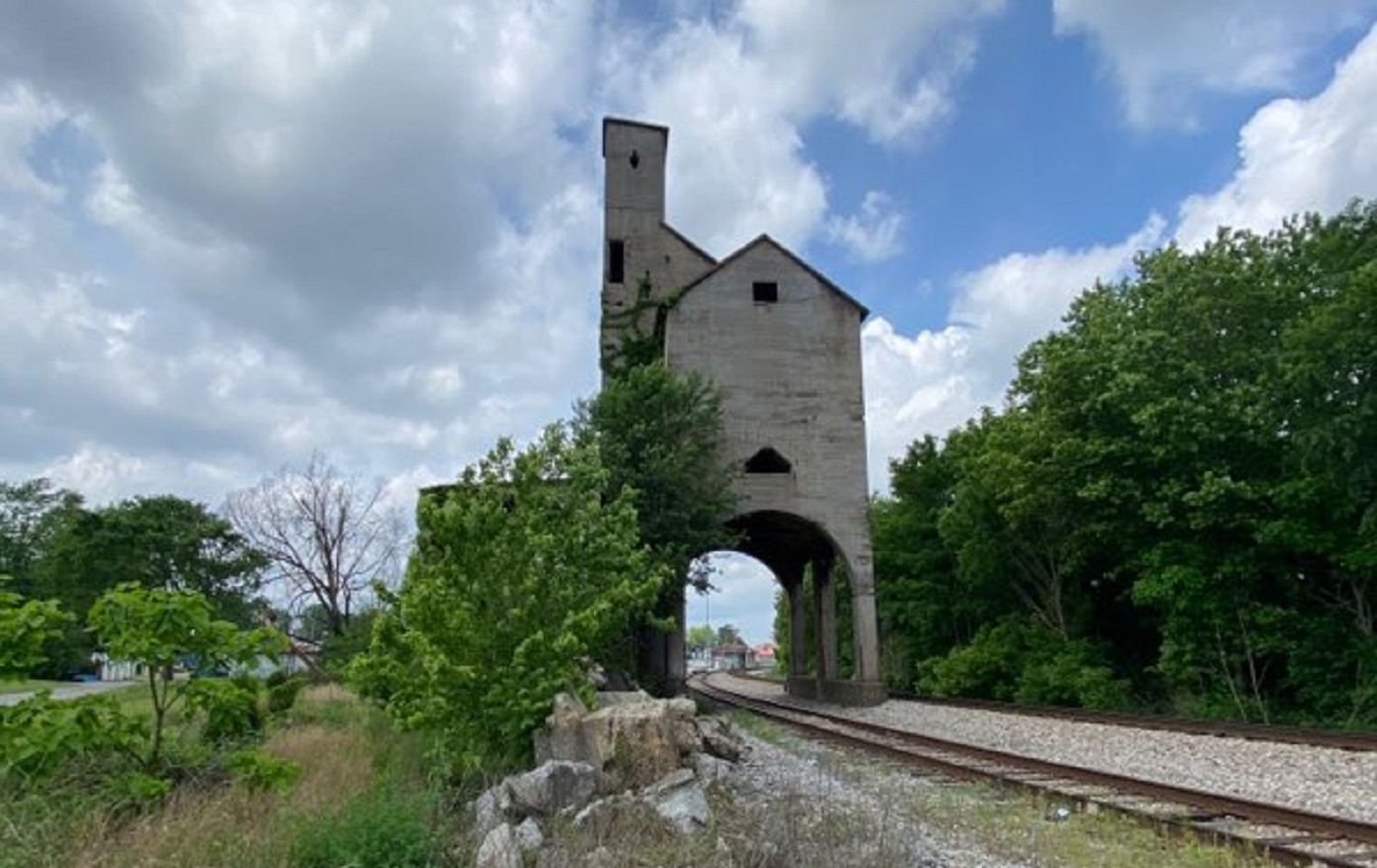 A building with a tunnel underneath with a railroad track underneath.